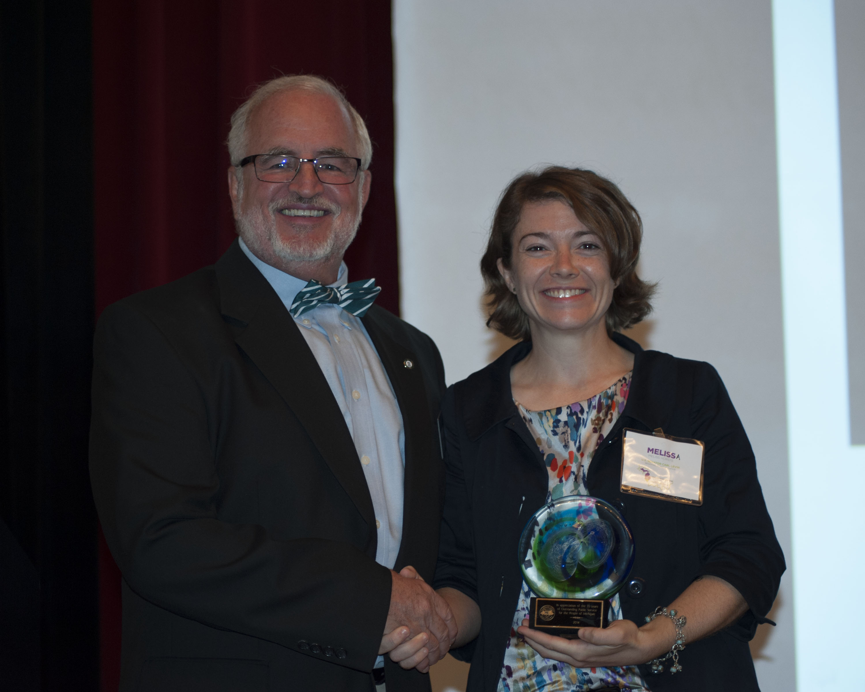 Photo of Senator Levin's representative, Melissa Horste, accepting a plaque from MSU CCED Director, Dr. Rex LaMore.
