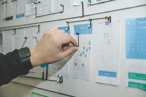 Person pinning strings on bulletin board