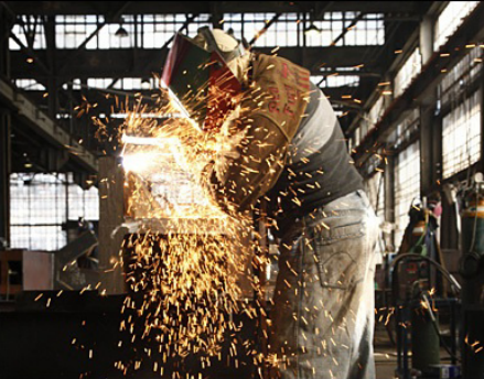 Photo of man in a welding mask creating a shower of sparks